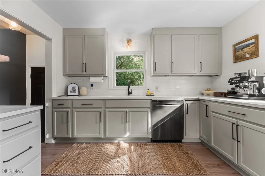 Kitchen with gray cabinets, dishwasher, decorative backsplash, and light wood-type flooring