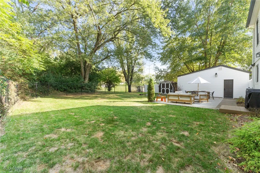 Fenced backyard featuring a deck, a storage shed, and outdoor lounge area