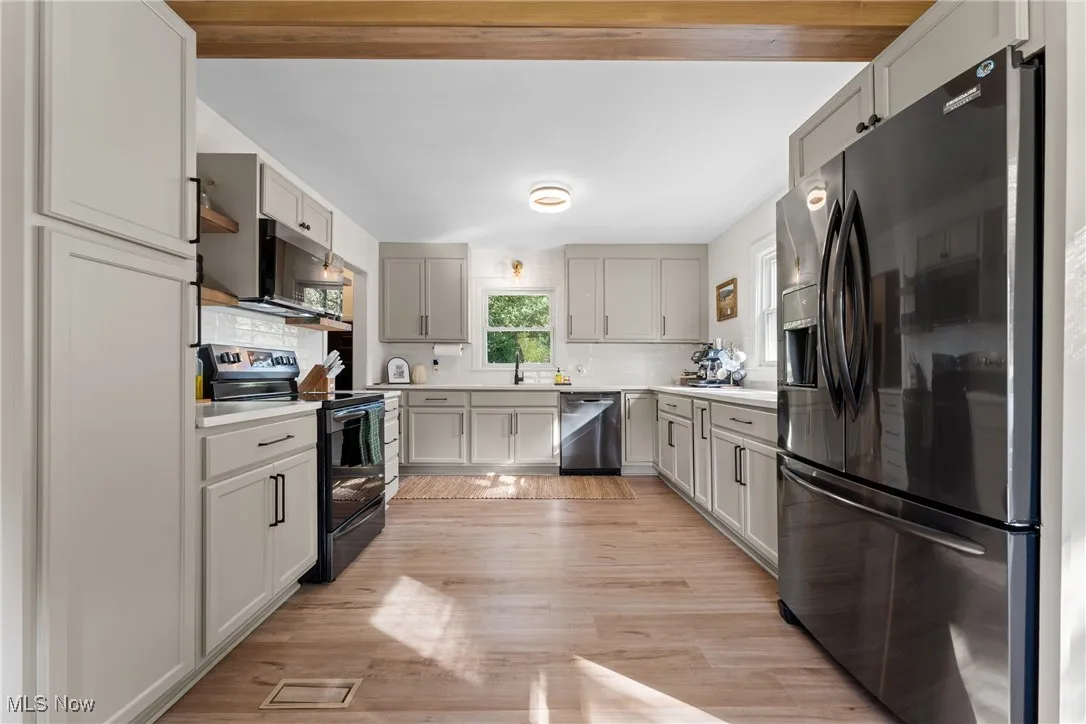Kitchen featuring stainless steel appliances, backsplash, light countertops, and light wood-style flooring