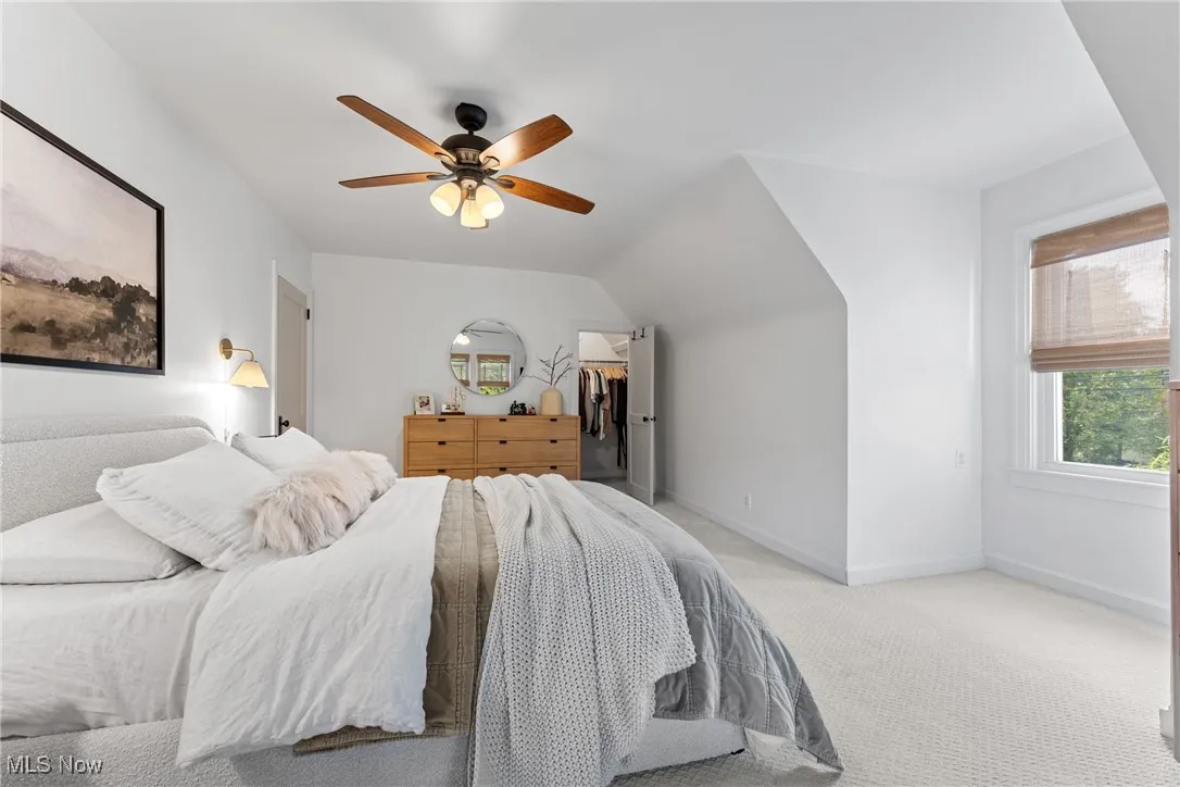 Bedroom featuring carpet, ceiling fan, a walk in closet, and vaulted ceiling