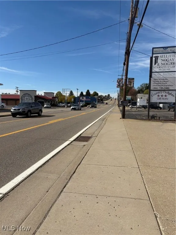 View of asphalt road featuring sidewalks and curbs