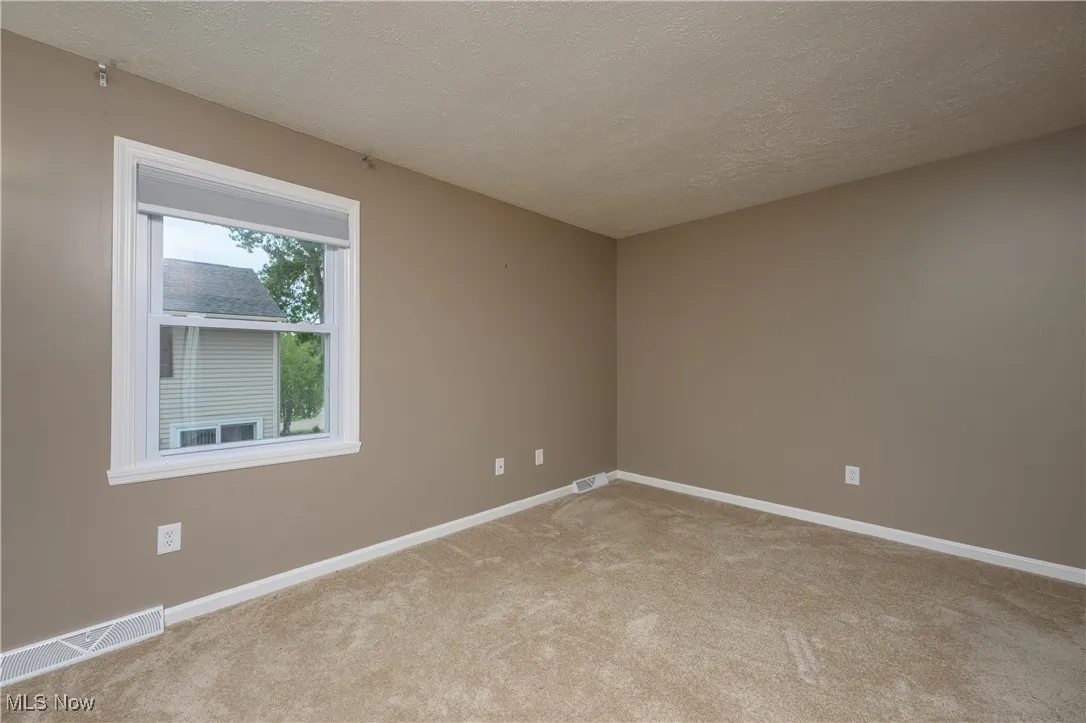 Spare room featuring a textured ceiling and light carpet
