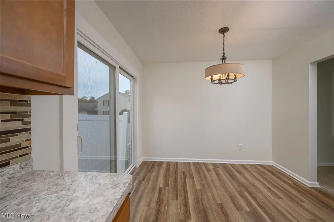 Unfurnished dining area featuring dark wood finished floors and baseboards