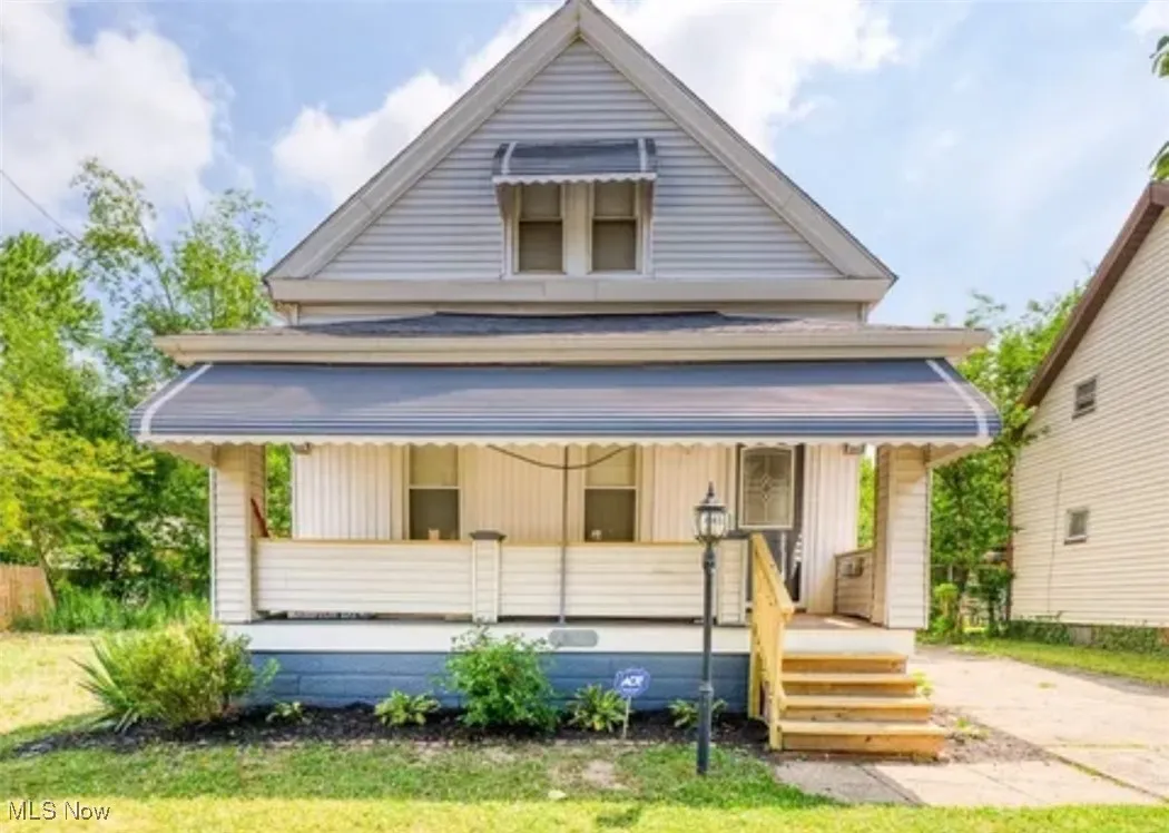 View of house with covered porch and a yard