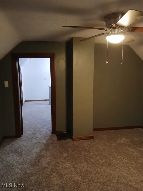 Hall with vaulted ceiling, carpet floors, and a textured ceiling