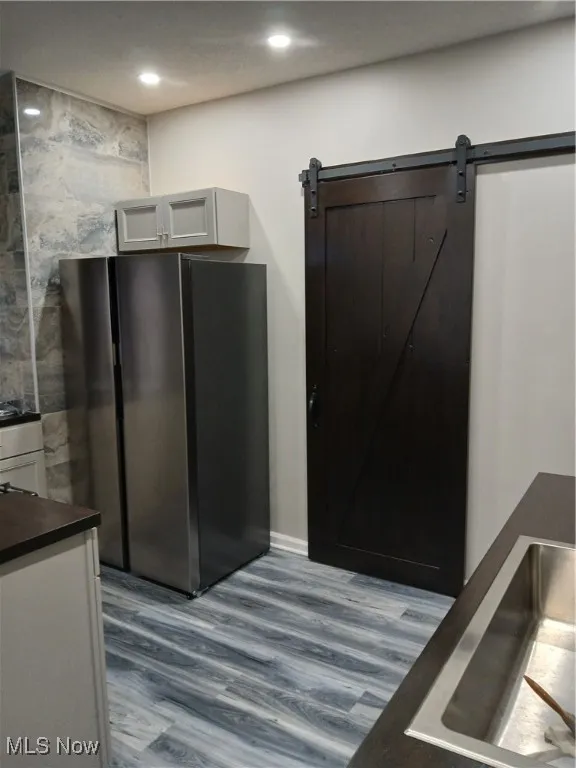 Kitchen area with light wood-style flooring, a barn door, and recessed lighting