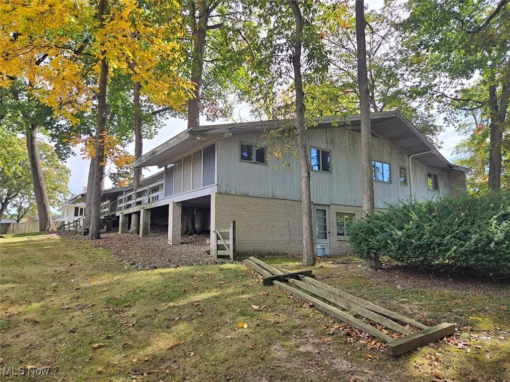 View of property exterior with brick siding, a lawn, and a wooden deck