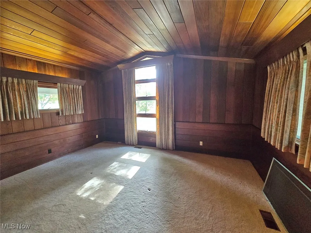 Carpeted bedroom featuring wood walls, wooden ceiling, plenty of natural light, and lofted ceiling