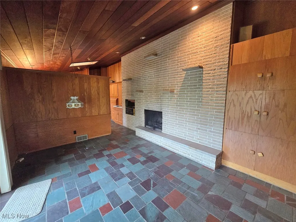 Dining area featuring wood walls, a brick fireplace, and wooden ceiling