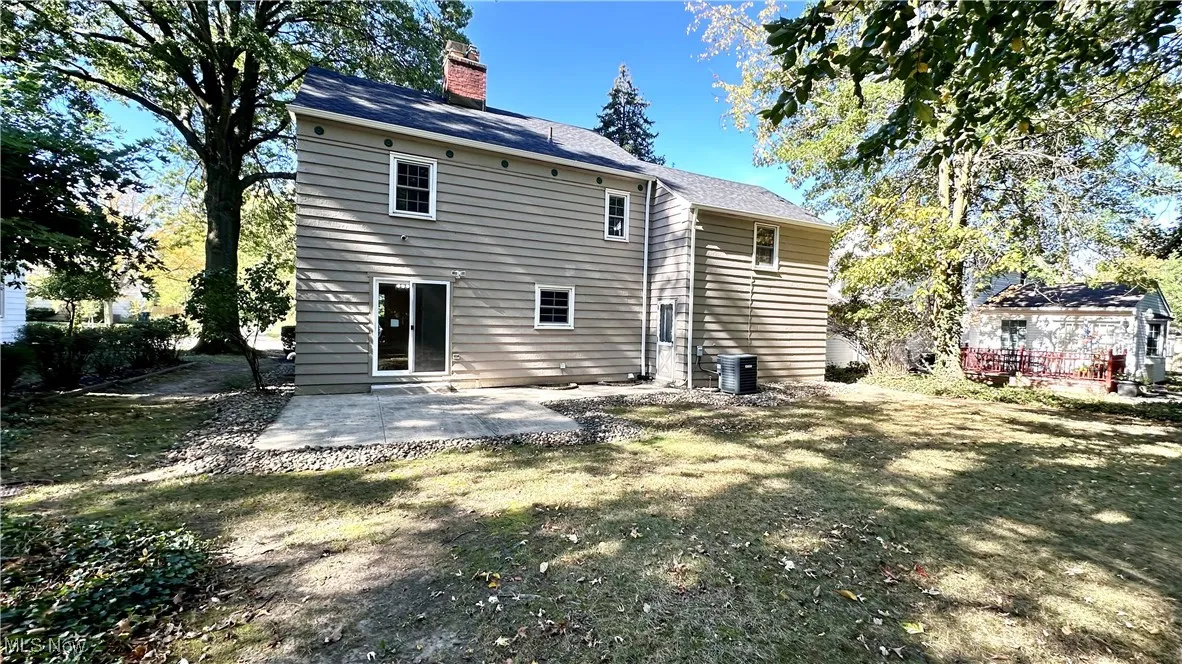 Back of property featuring a patio, a chimney, and a lawn