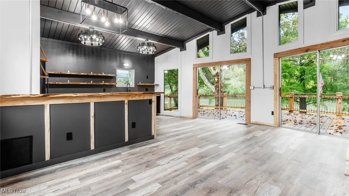 Kitchen with open shelves, wood counters, high vaulted ceiling, light wood-style floors, and a wooden ceiling with exposed beams