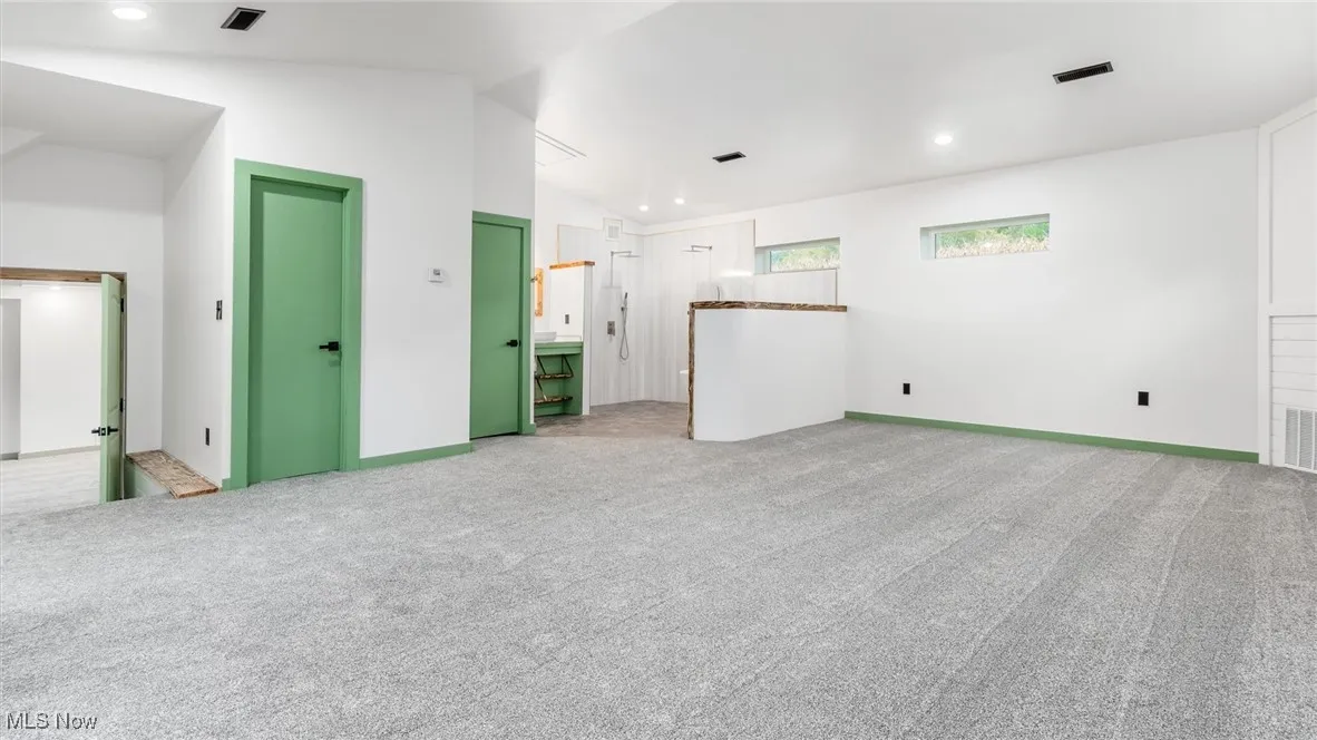 Empty room with lofted ceiling, light carpet, and recessed lighting