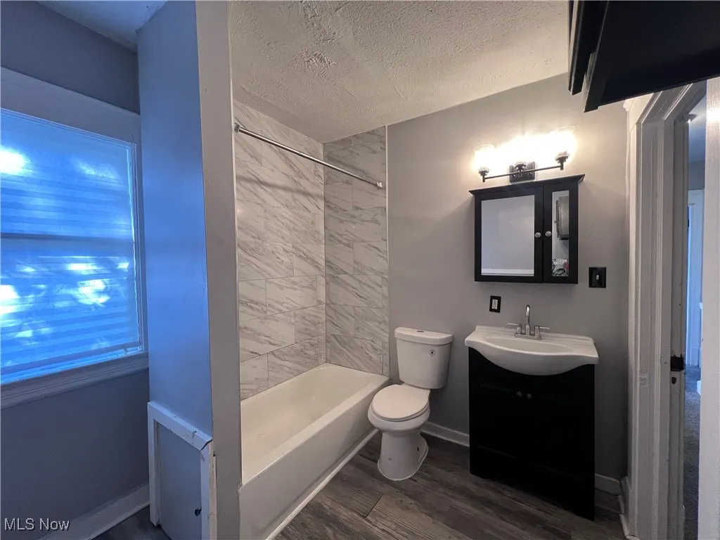 Full bathroom featuring dark wood-style flooring, a textured ceiling, vanity, and bathing tub / shower combination
