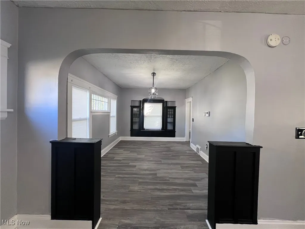 Foyer entrance featuring arched walkways, a textured ceiling, and wood finished floors