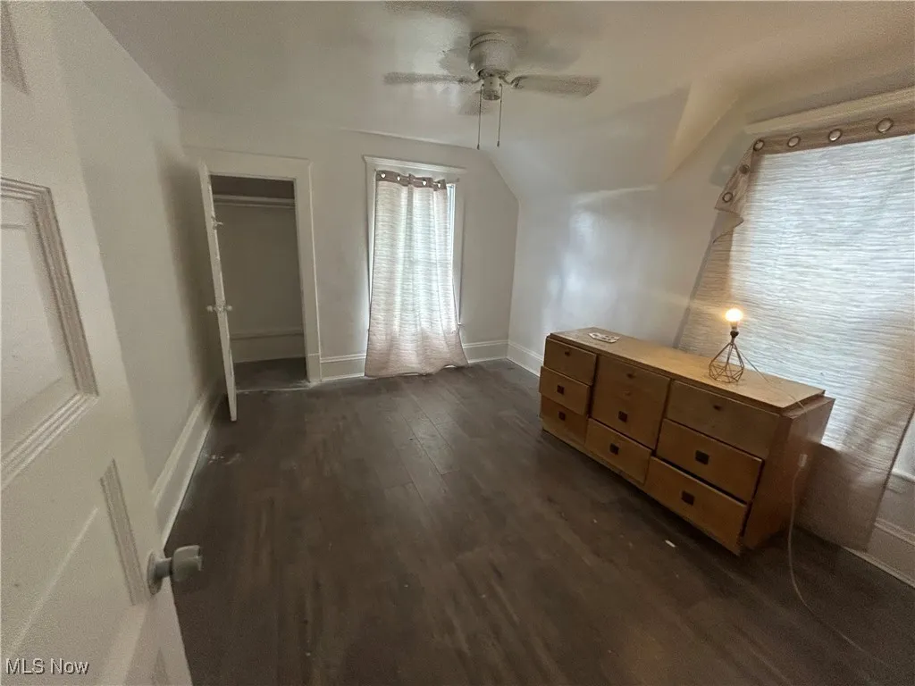 Unfurnished bedroom with dark wood-type flooring, a ceiling fan, and vaulted ceiling