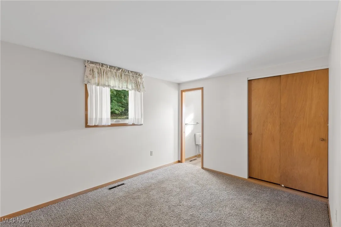 Unfurnished bedroom featuring ensuite bathroom, carpet floors, and a closet