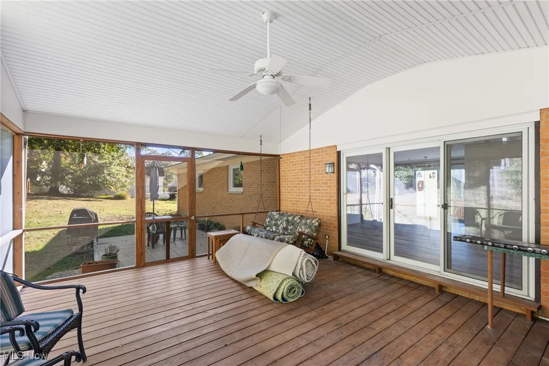 Sunroom featuring lofted ceiling, ceiling fan, and a wooden deck