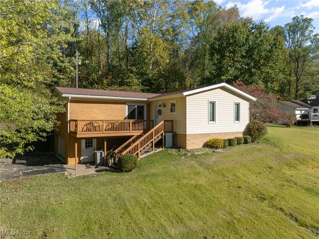 Back of property featuring a lawn, a wooden deck, stairs, and asphalt driveway