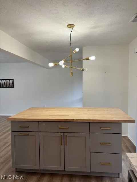 Kitchen featuring a textured ceiling, decorative light fixtures, dark wood finished floors, gray cabinets, and a chandelier