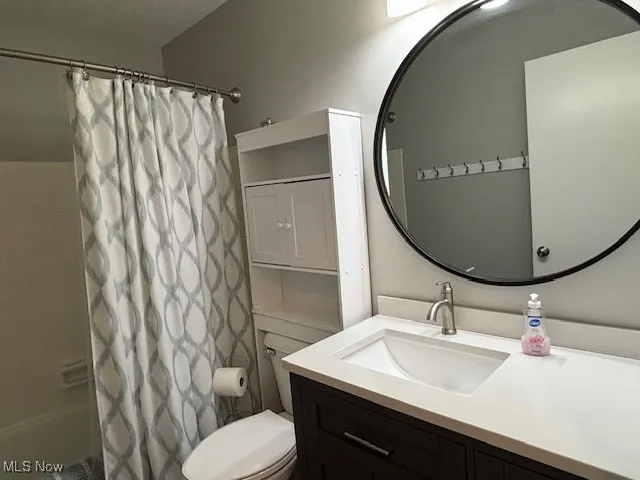 Bathroom with shower / bath combination with curtain and vanity