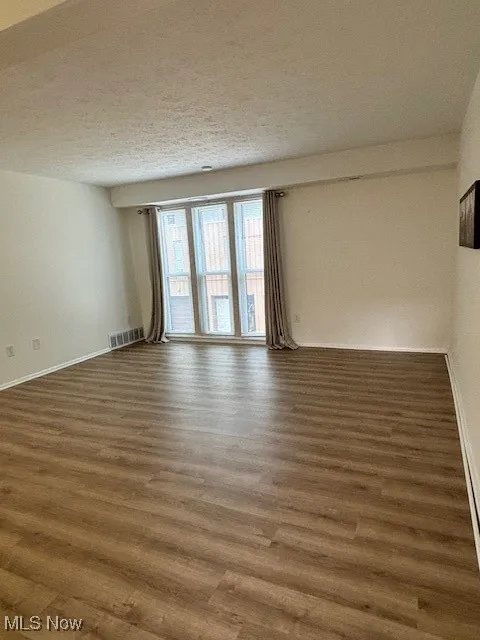 Empty room featuring a textured ceiling and wood finished floors