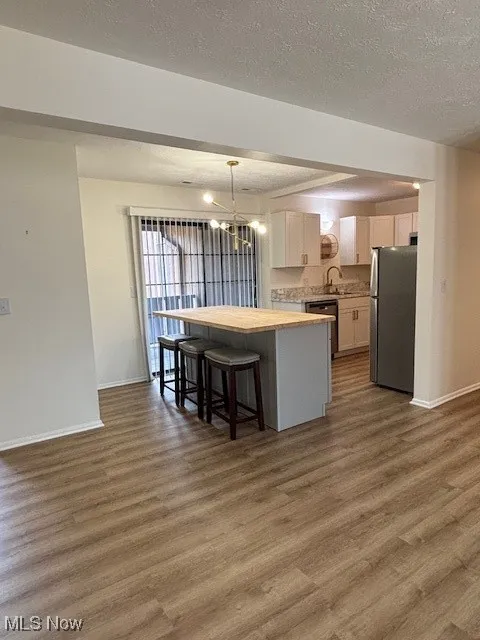 Kitchen featuring a center island, light countertops, a chandelier, a breakfast bar area, and dark wood-type flooring