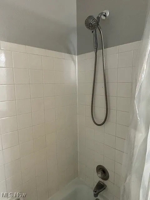 Bathroom view of shower / bath combo with shower curtain