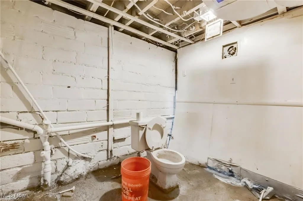 Bathroom featuring concrete flooring and concrete block wall