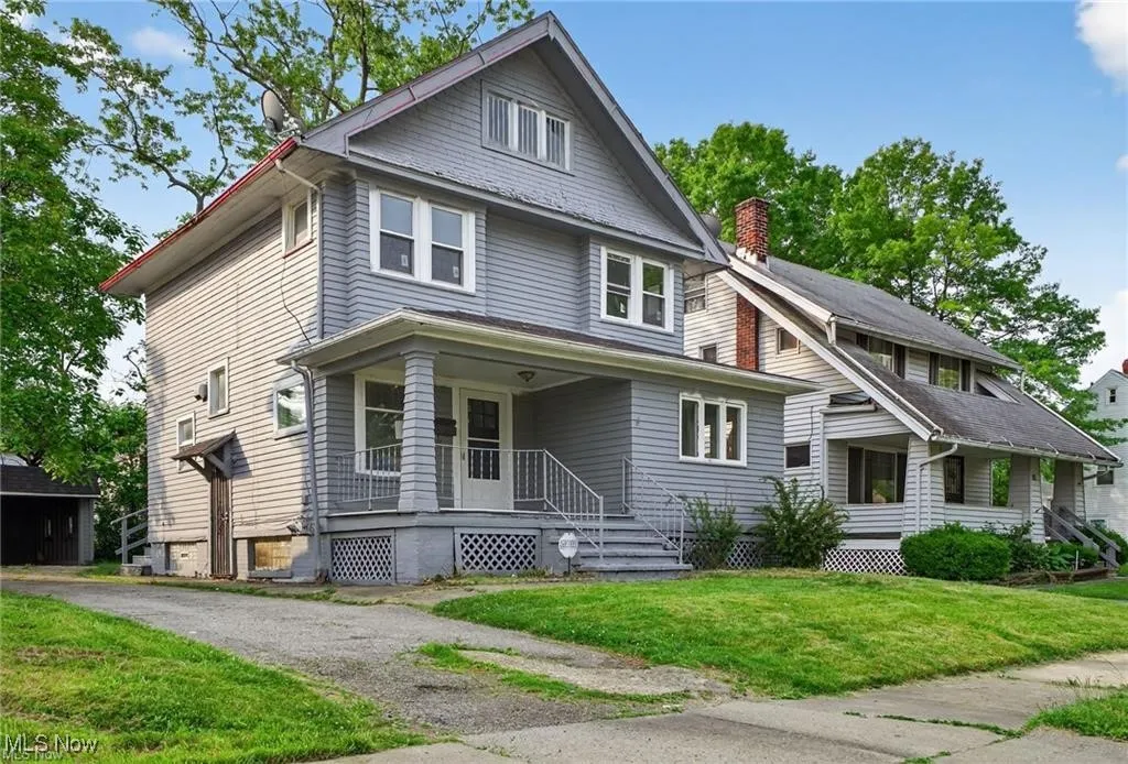 American foursquare style home with a porch, a front yard, and a chimney