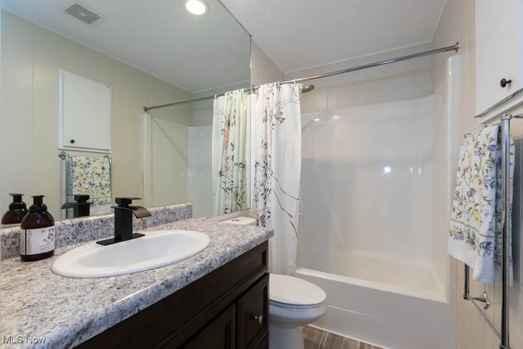 Bathroom with shower / tub combo, vanity, and recessed lighting