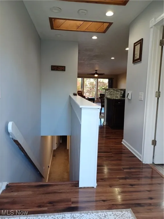 Hallway featuring an upstairs landing, recessed lighting, and dark wood-style floors