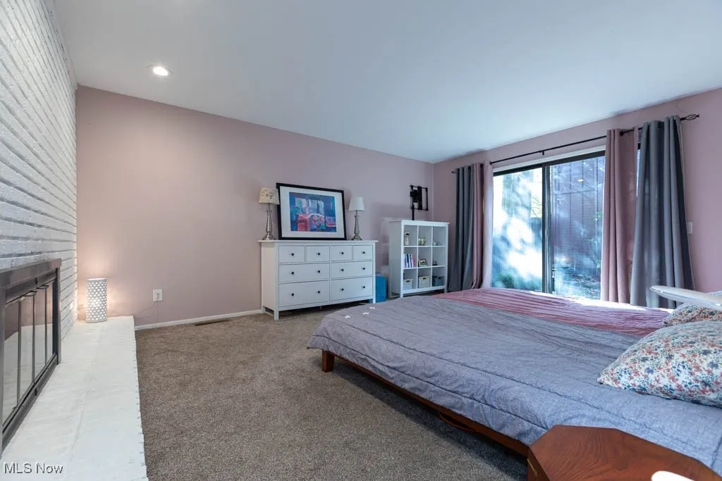 Bedroom with carpet floors and a brick fireplace