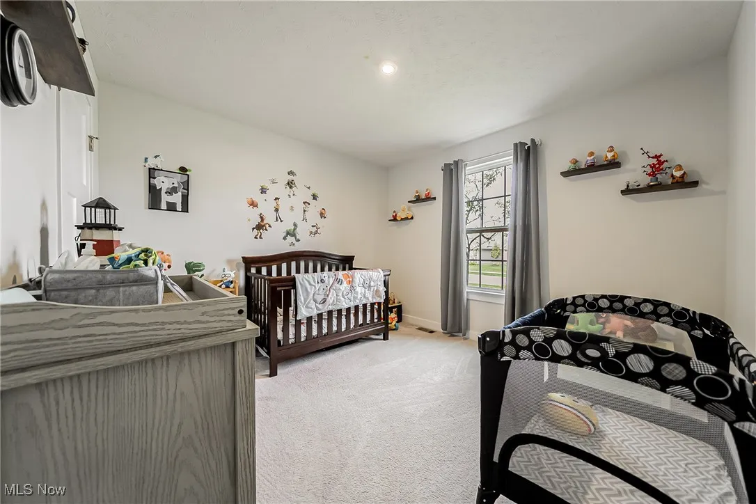 Bedroom featuring light carpet and a crib