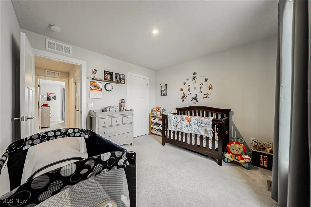 Bedroom featuring a crib and light colored carpet