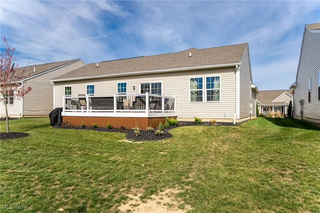 Rear view of house featuring a deck, a shingled roof, and a yard