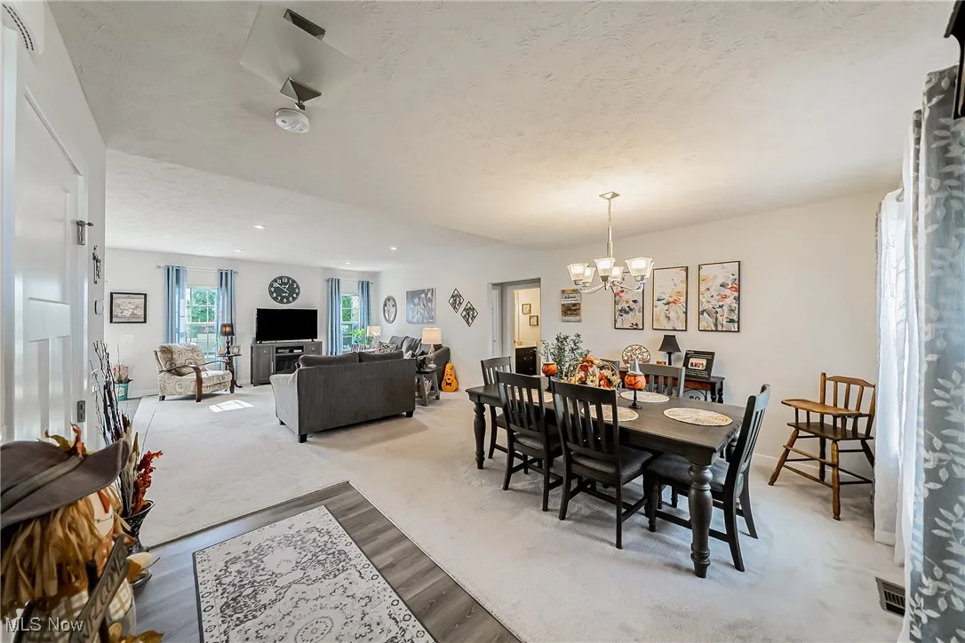 Dining room with light carpet, a textured ceiling, and a chandelier
