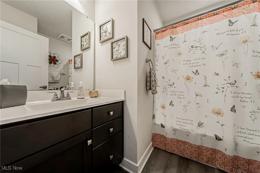 Full bath featuring vanity, curtained shower, and dark wood-style flooring