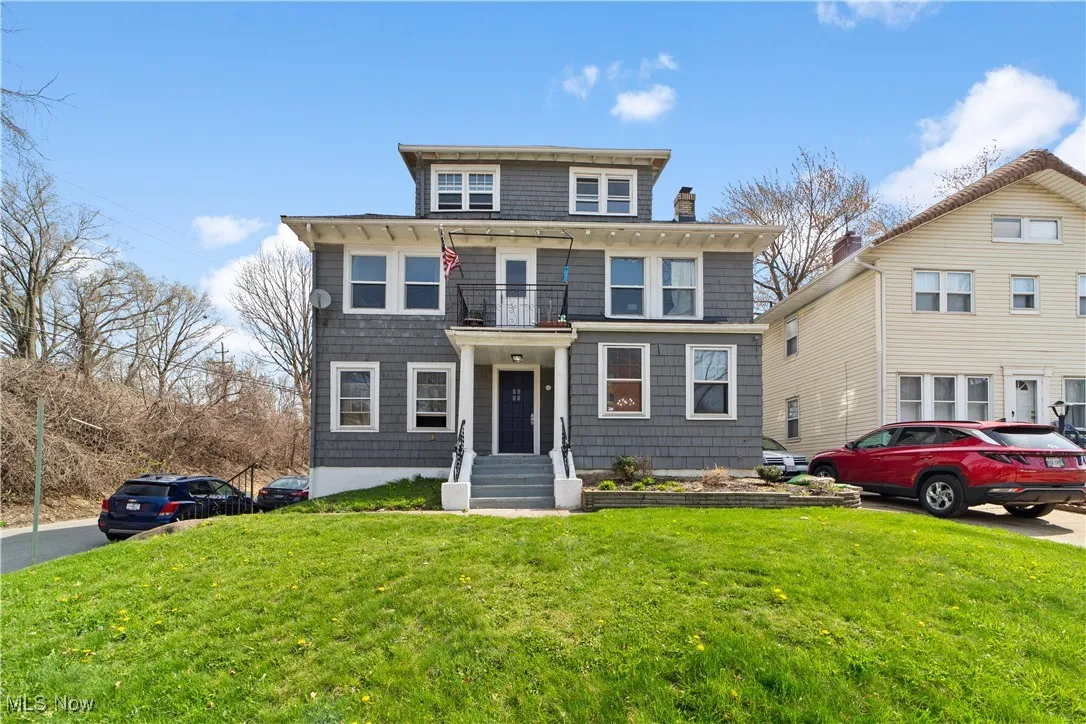 American foursquare style home with a front yard, a balcony, and a chimney