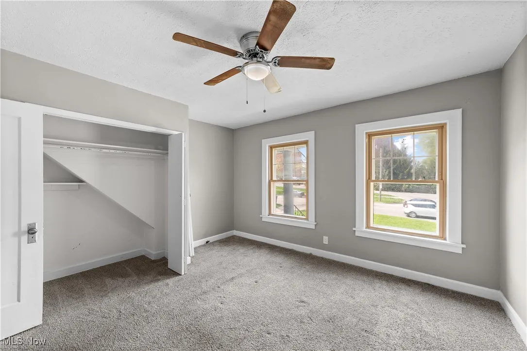 Unfurnished bedroom featuring carpet floors, a textured ceiling, a closet, and a ceiling fan