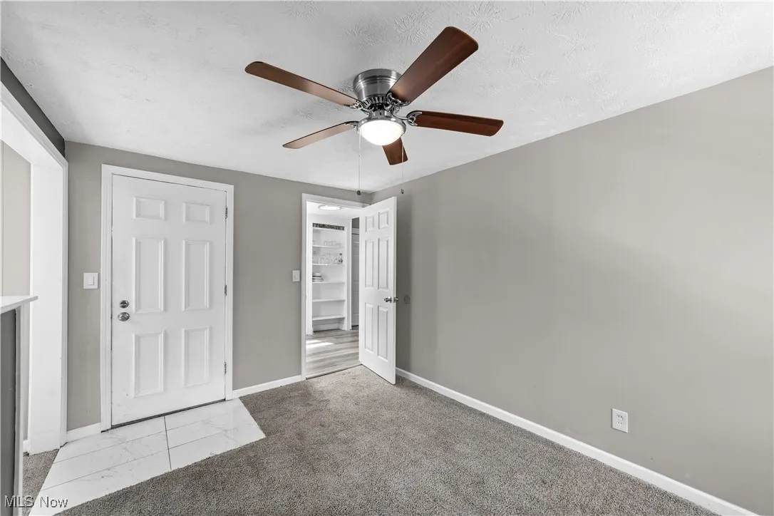 Unfurnished bedroom featuring light carpet, a textured ceiling, and ceiling fan