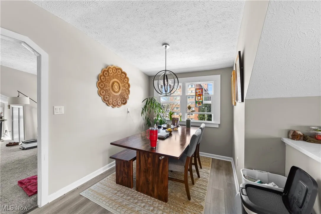 Dining room with a textured ceiling, wood finished floors, arched walkways, and a chandelier