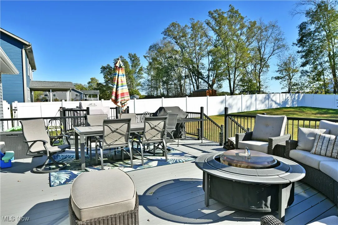 Wooden deck with outdoor dining area, a fenced backyard, and an outdoor living space with a fire pit