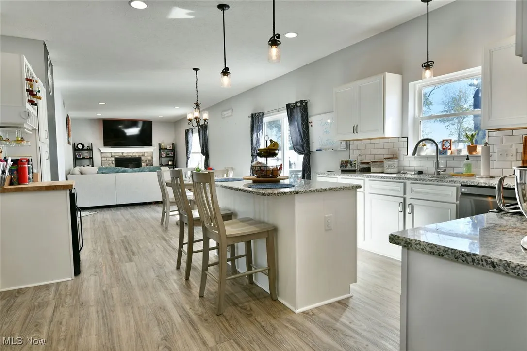Kitchen featuring a kitchen breakfast bar, white cabinetry, hanging light fixtures, light wood-type flooring, and recessed lighting