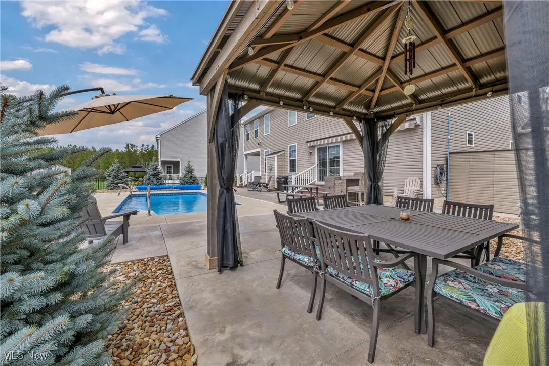View of patio with a gazebo, an outdoor pool, and outdoor dining area