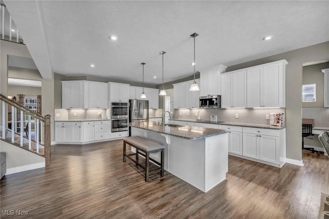 Kitchen with white cabinets, a breakfast bar area, dark wood-style flooring, a textured ceiling, and recessed lighting