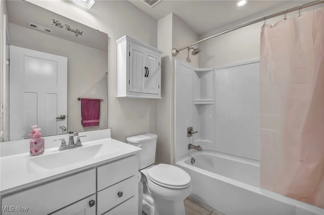 Full bathroom featuring shower / bathtub combination with curtain, vanity, and light tile patterned floors