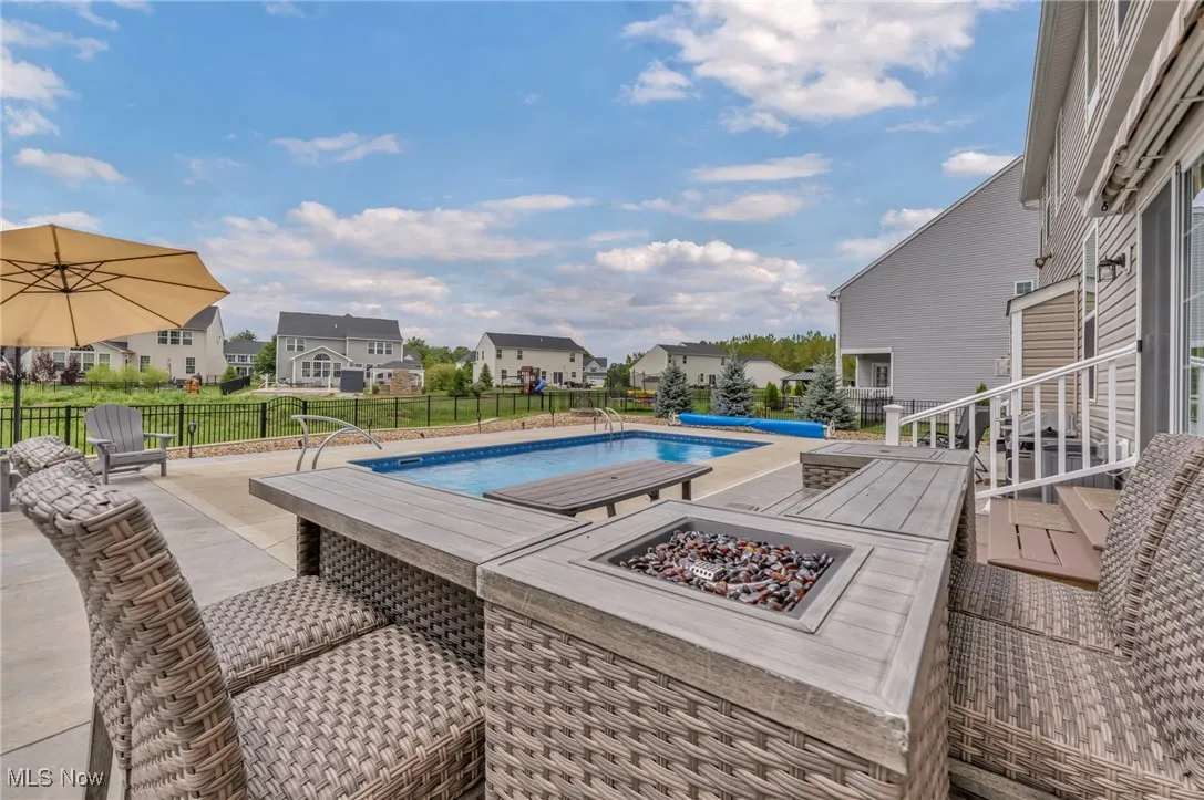 View of swimming pool with an outdoor fire pit, a fenced backyard, a residential view, and a patio