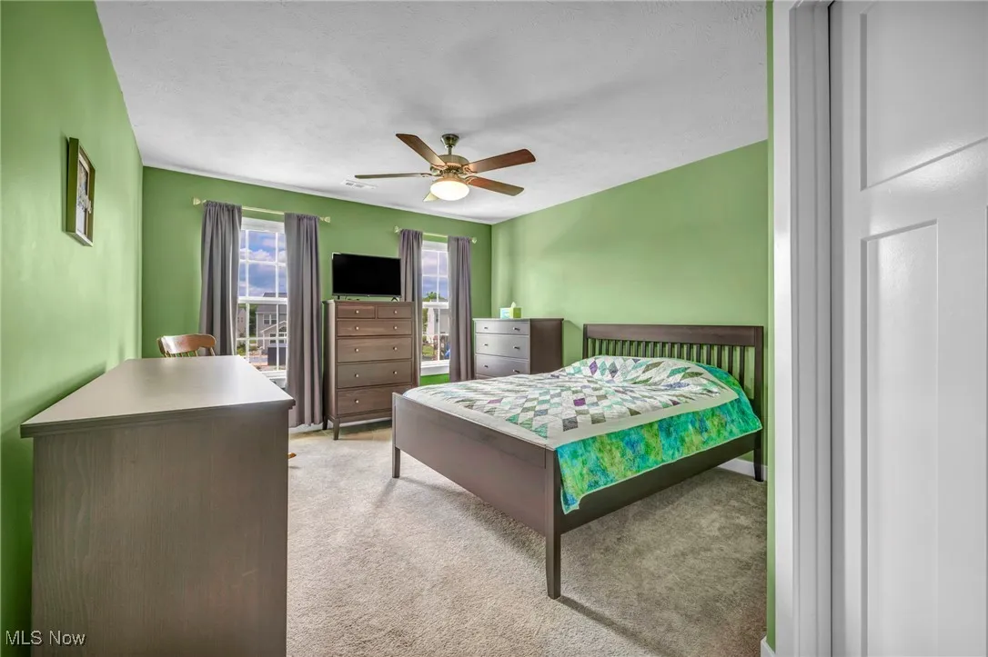 Carpeted bedroom featuring a ceiling fan and a textured ceiling