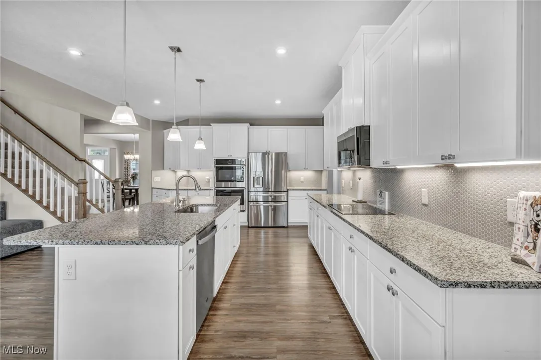 Kitchen with appliances with stainless steel finishes, white cabinetry, tasteful backsplash, light stone countertops, and recessed lighting
