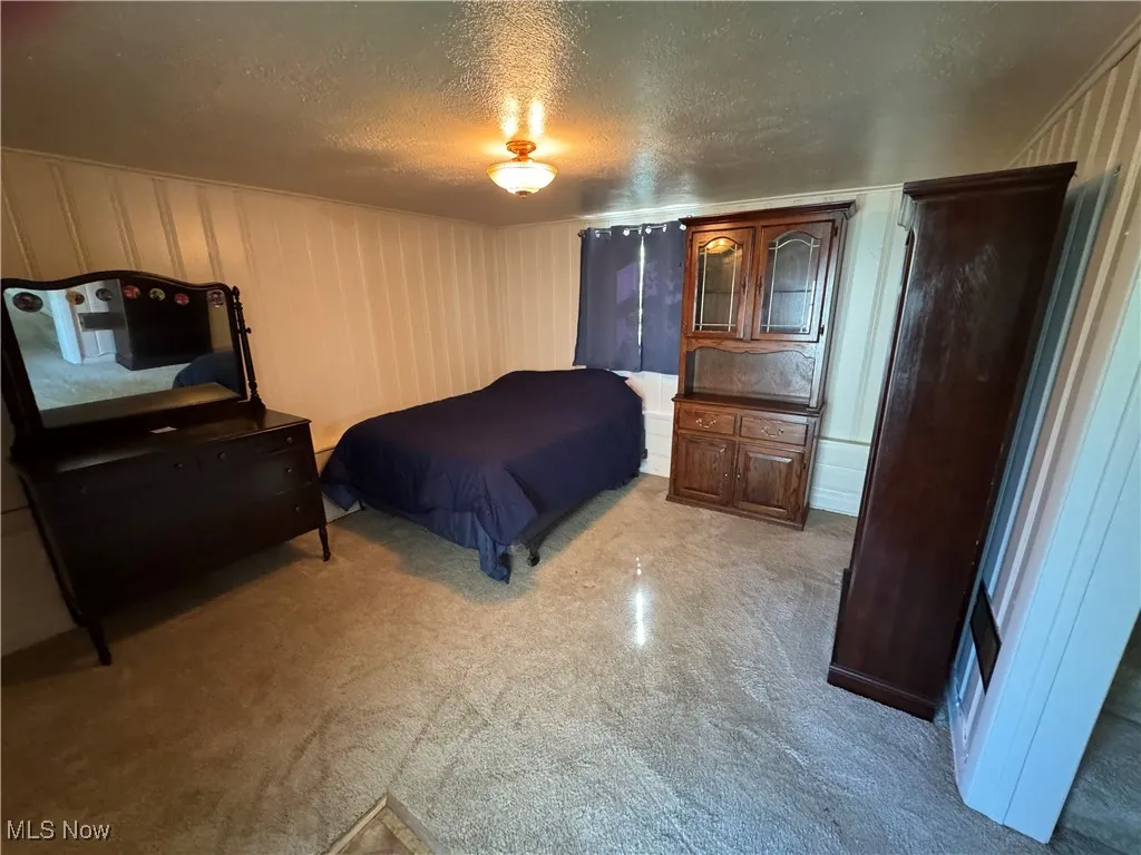 Bedroom featuring a textured ceiling and light carpet